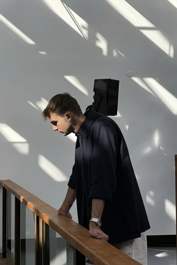 Quentin Freycenon, leaning on a railing in a workshop crossed by the sun.